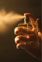 Hand holding a perfume bottle spraying a cloud of mist against a dark background